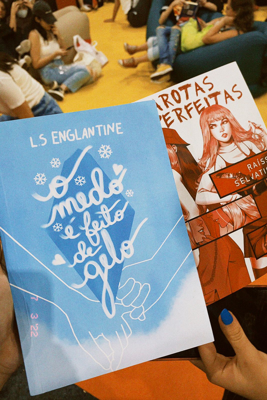 Livro de capa azul com o título "O medo é feito de gelo", escrito por L.S. Englantine e atrás tem um livro com a ilustração vermelha de duas garotas com o título "Garotas (Im)perfeitas".