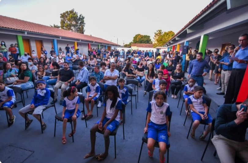 fotografia mostra estudantes da rede pública sentados em cadeiras em pátio a céu aberto