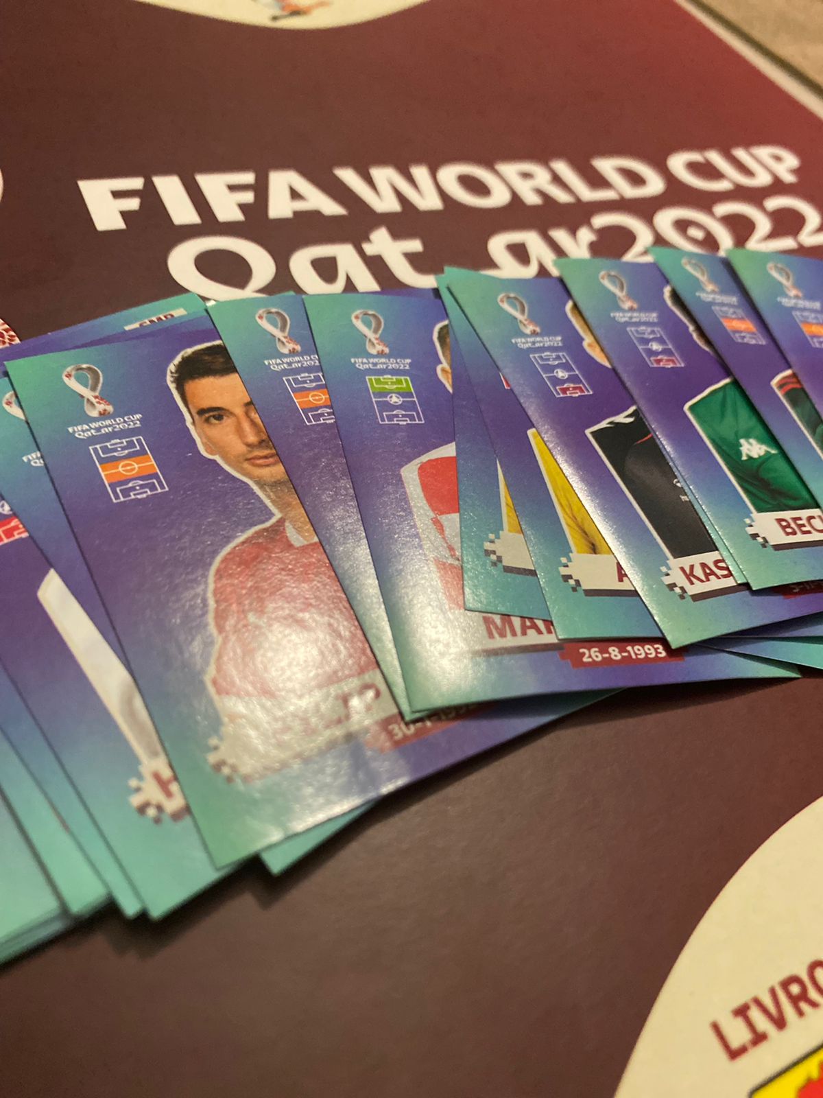 fotografia mostra figurinhas do álbum da copa do mundo de 2022 espalhadas sobre uma superfície