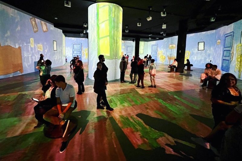 Visitantes admiram representação da obra "Quarto em Arles", de Van Gogh, exposta nas paredes do local da exibição.