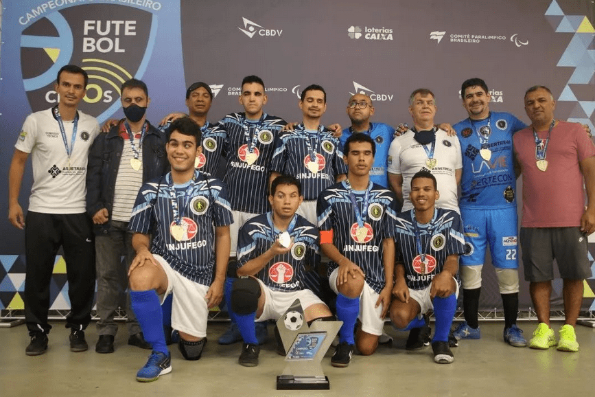 fotografia mostra atletas de futebol de cegos posando para foto.