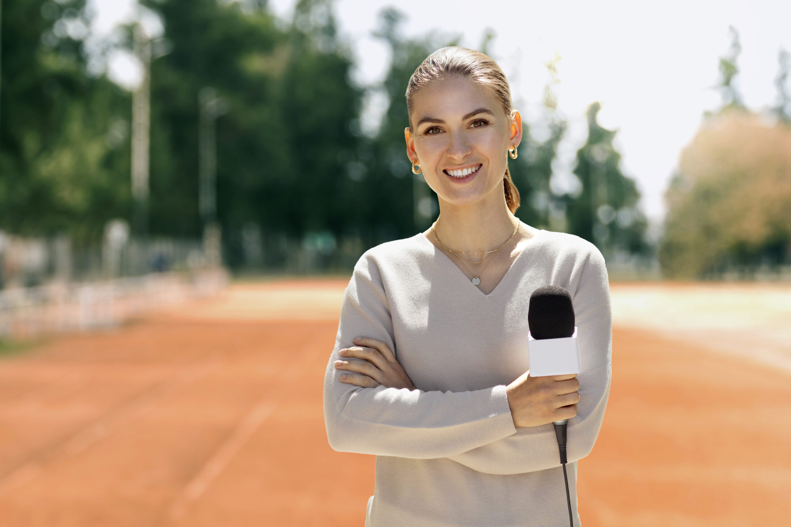 Jornalista mulher segurando um microfone em um ambiente esportivo.