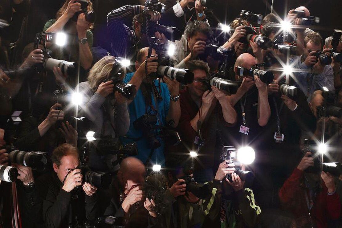 Fotógrafos tirando fotos de alguém