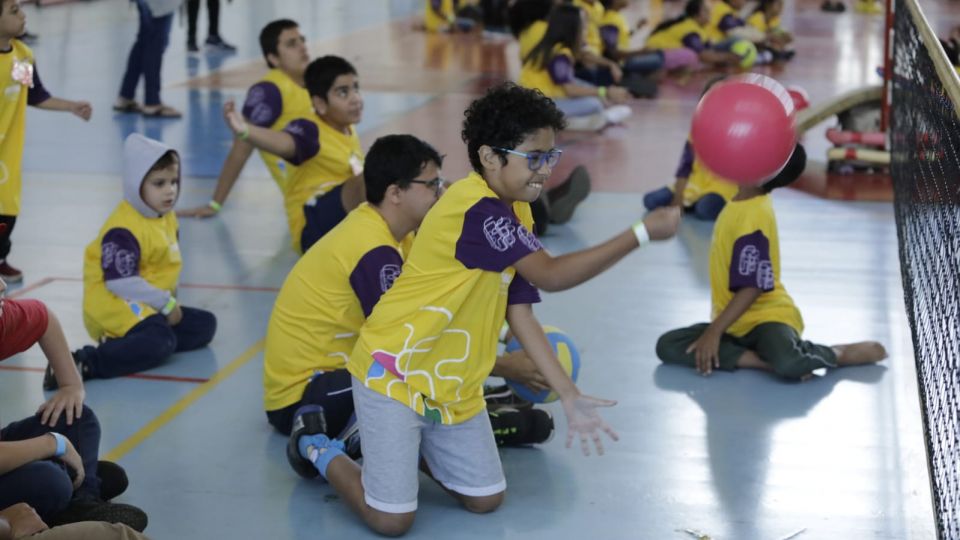 Crianças sentadas jogando com uma bola.