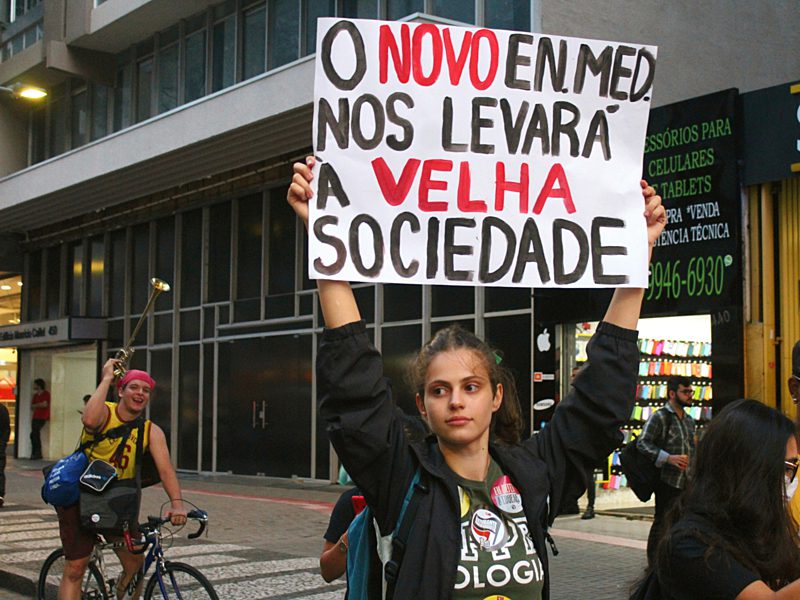 Na imagem, estudantes parte do Levante Popular da Juventude, movimento estudantil, participam de manifestação contra o Novo Ensino Médio com cartazes.
