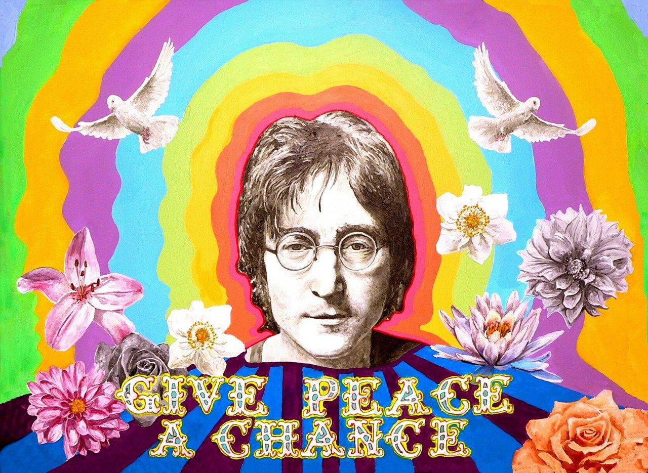 Na imagem, é retratado o cantor John Lennon da banda dos Beatles rodeado por cores e pombas brancas em um estilo psicodélico. Em destaque, a frase: Dê uma chance para a paz