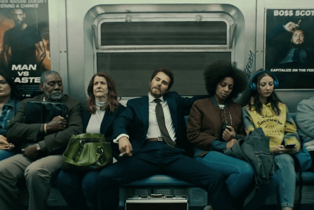 Homem de terno com as pernas abertas dentro do metrô