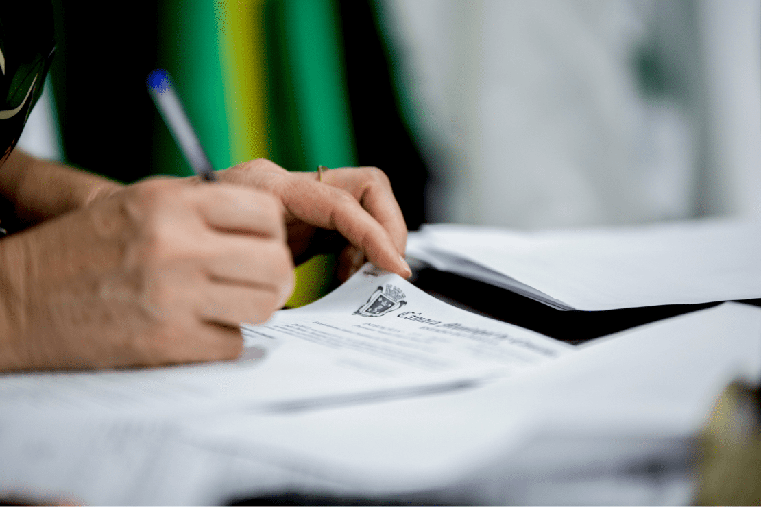 mão segurando uma caneta e assinando um papel