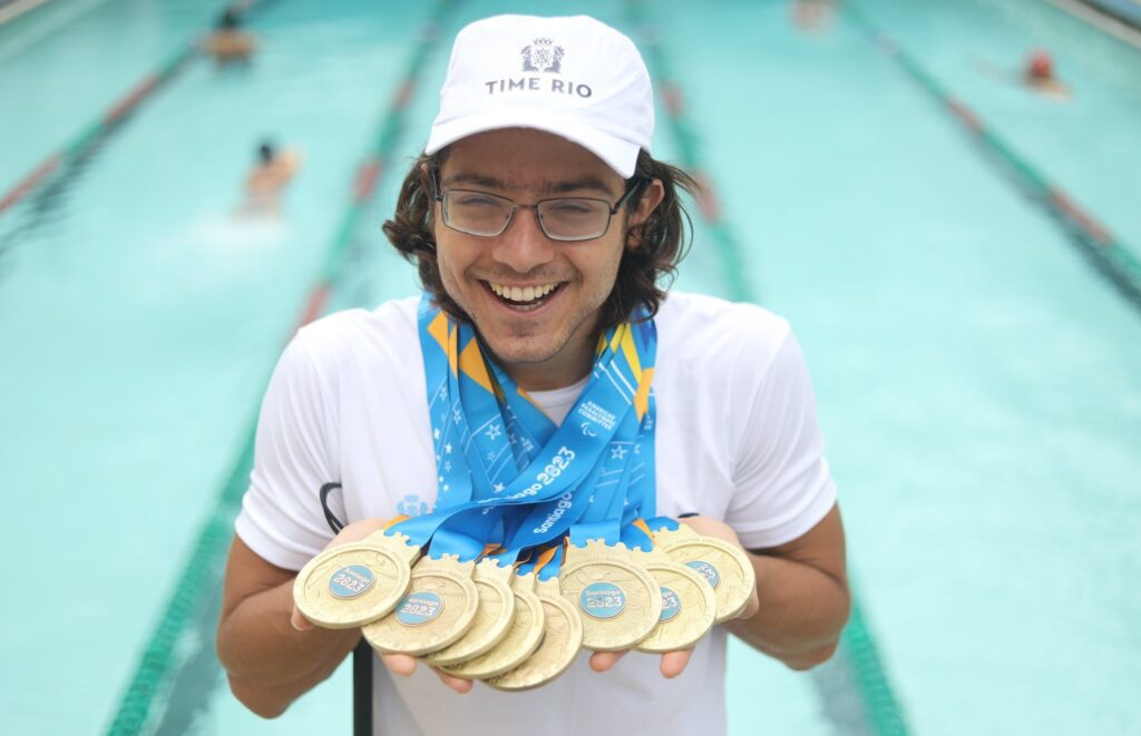 Nadador Douglas Matero sorri enquanto mostra suas oito medalhas medalhas
