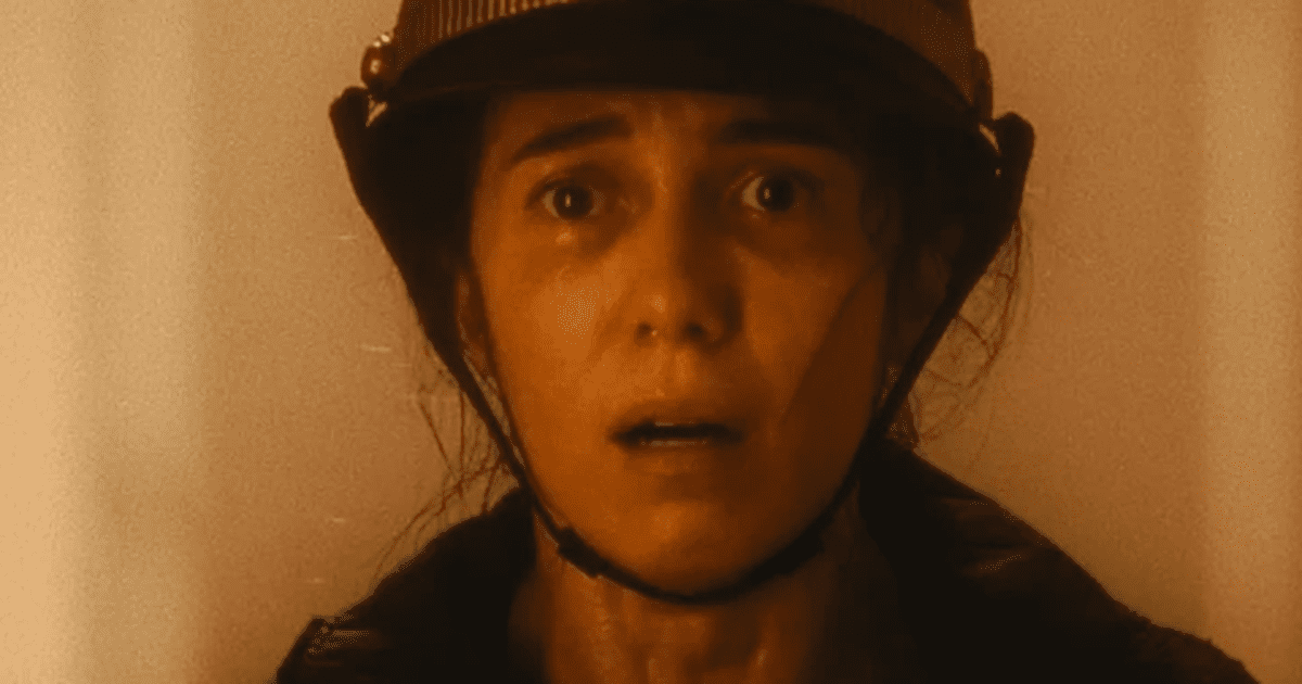 Marjorie Estiano, mulher branca com chapéu de bombeiro, olhando assustada em direção à câmera